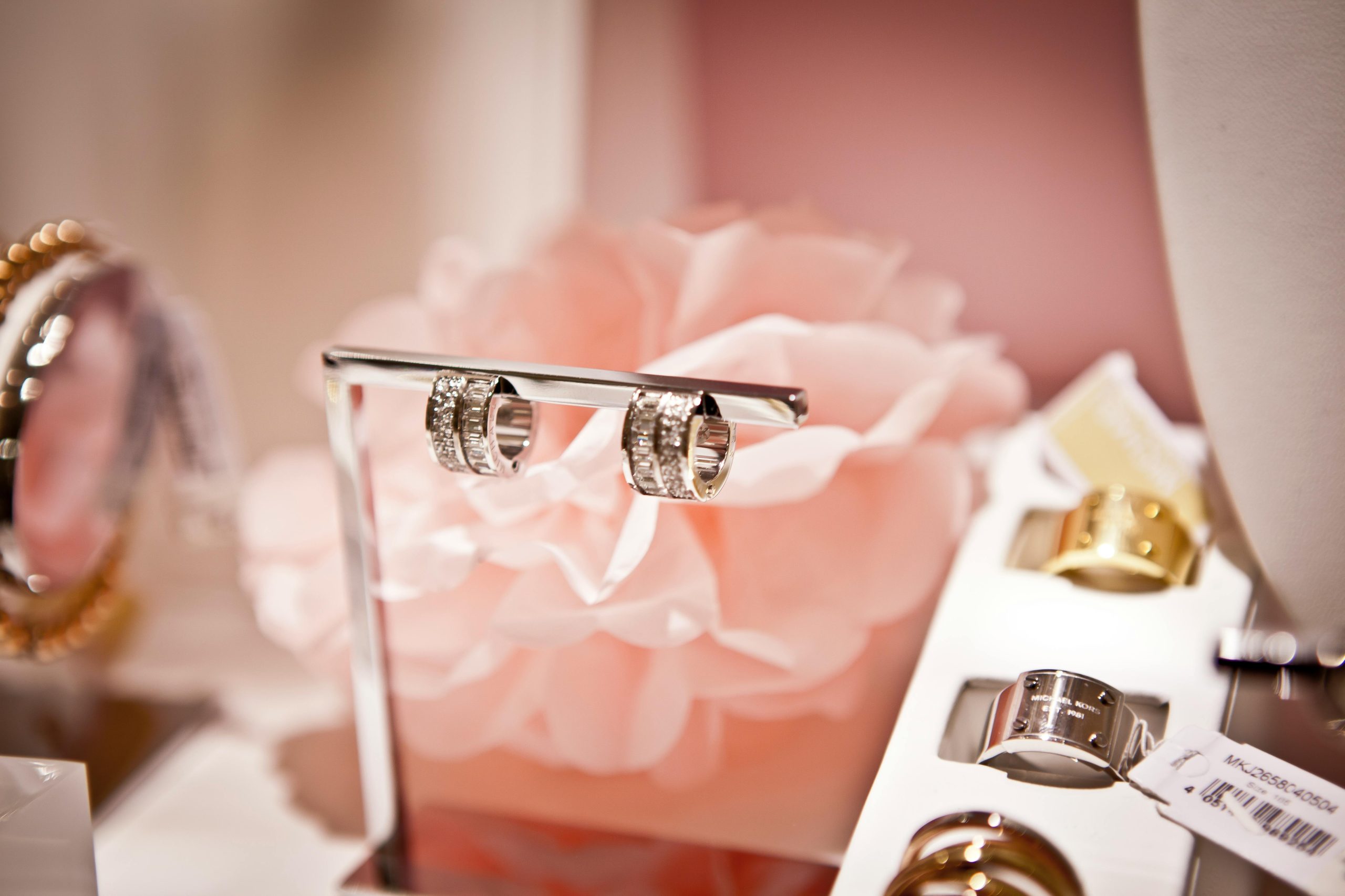 Close-up of diamond wedding rings displayed elegantly against a soft pink floral backdrop.
