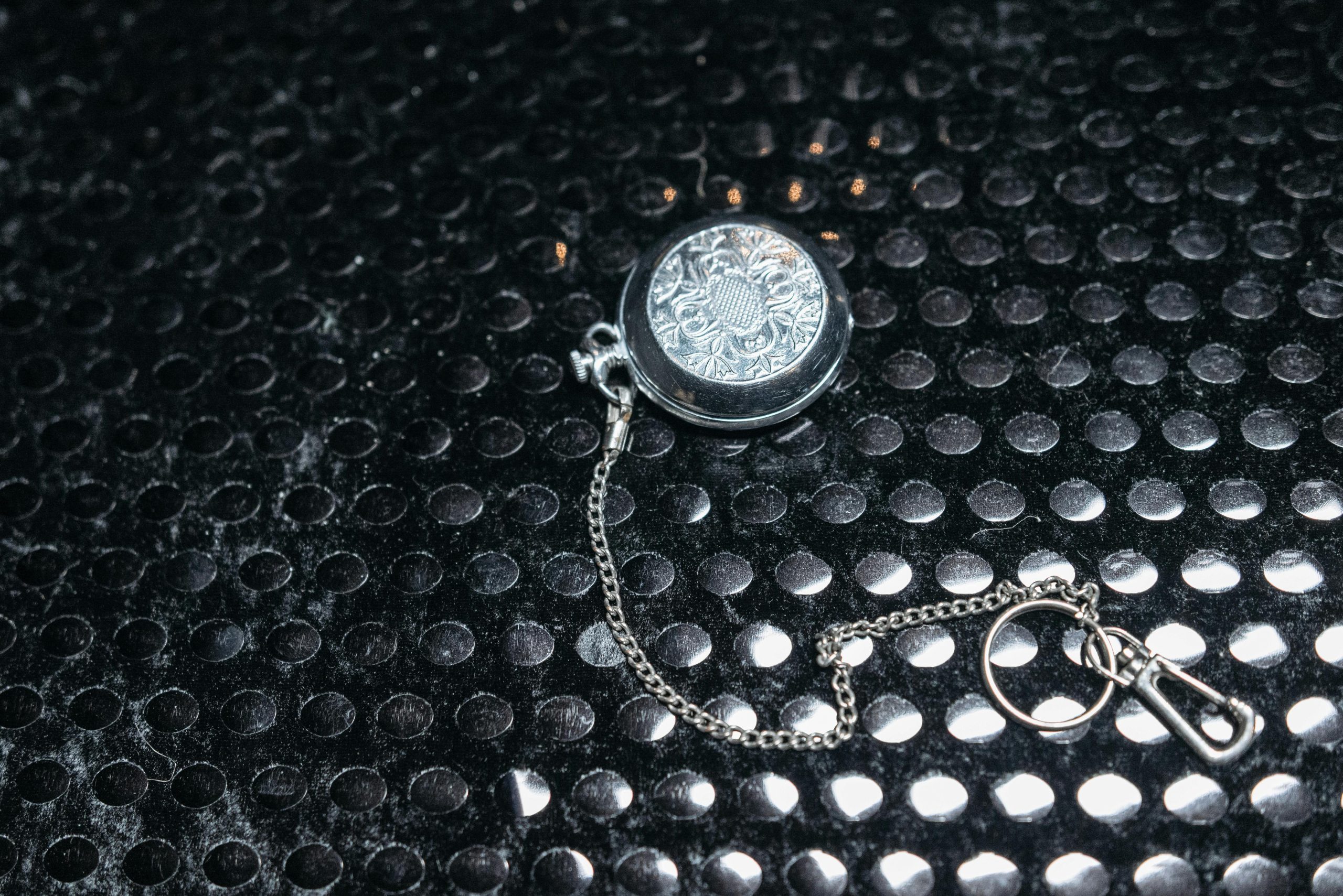 Ornate silver locket with chain, elegantly displayed on black textured background. Perfect for themes of elegance and mystery.